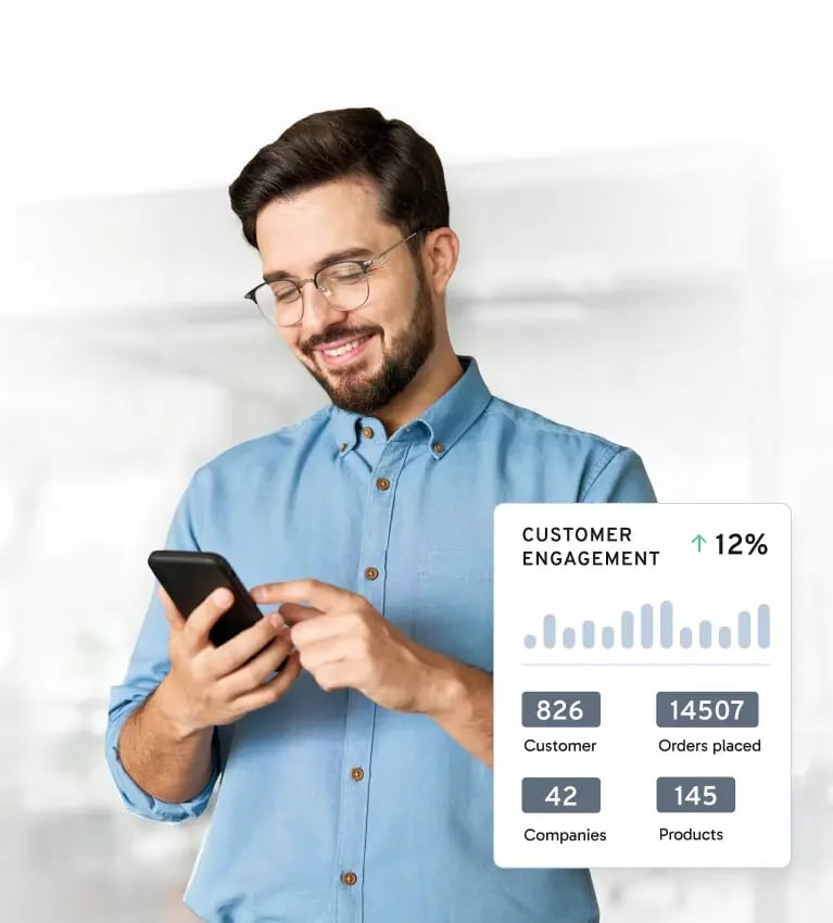A person in a blue shirt holds a smartphone, displaying customer engagement statistics in a bright, modern office setting.